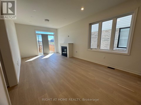 A spacious room with wooden flooring and a large window.