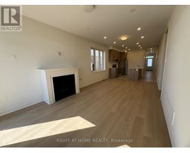 A spacious living room with a fireplace and wood flooring.
