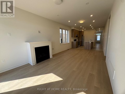 A spacious living room with a fireplace and wood flooring.
