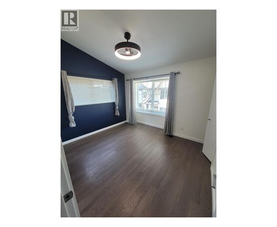 A room with a ceiling fan and a window with curtains.