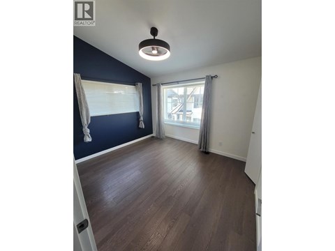 A room with a ceiling fan and a window with curtains.