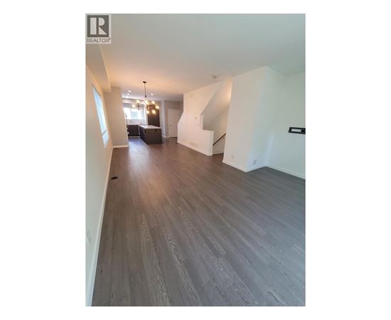 A spacious room with wooden flooring and a staircase.