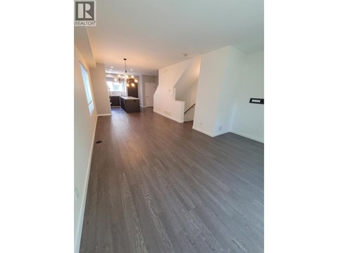 A spacious room with wooden flooring and a staircase.