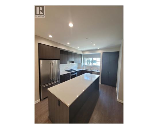 A modern kitchen with dark wood cabinets and stainless steel appliances.