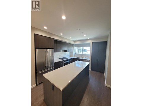 A modern kitchen with dark wood cabinets and stainless steel appliances.