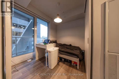 A bedroom with a bed, desk, and window.
