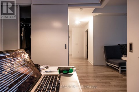 A laptop is open on a table with a green and black object next to it.