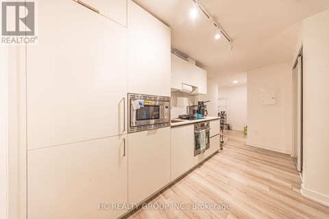 A kitchen with white cabinets and a refrigerator.