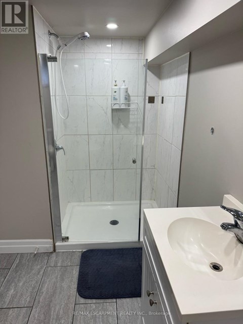 A bathroom with a sink, mirror, and walk-in shower.