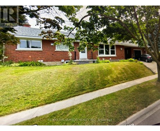 A house with a red brick exterior and a white door is surrounded by a green lawn.