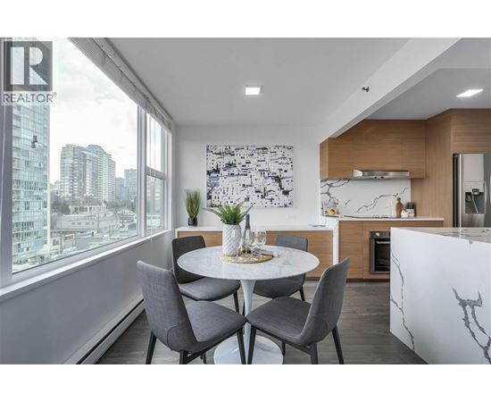 A modern dining room with a table set for two and a city view through the window.