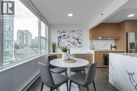A modern dining room with a table set for two and a city view through the window.