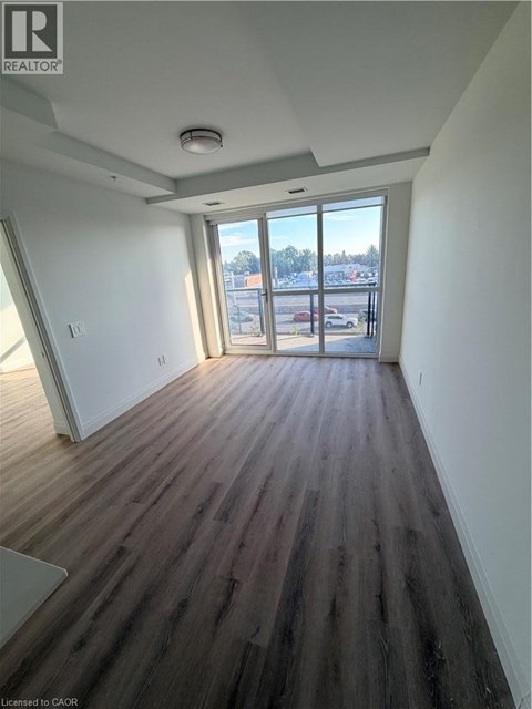 A room with wooden floors and a large window overlooking a parking lot.
