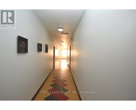 A long hallway with pictures on the wall and a light at the end.