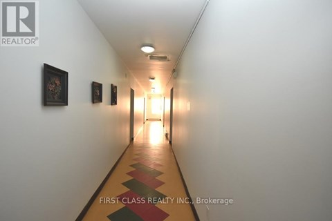 A long hallway with pictures on the wall and a light at the end.