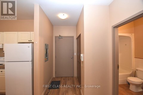 A hallway with a toilet and a sink visible through the door.