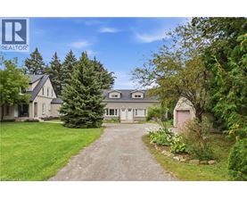 A house with a driveway and trees in front of it.