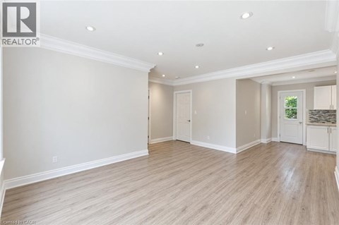 A spacious room with wooden flooring and white walls.
