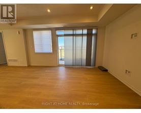 A spacious room with wooden flooring and a sliding glass door.