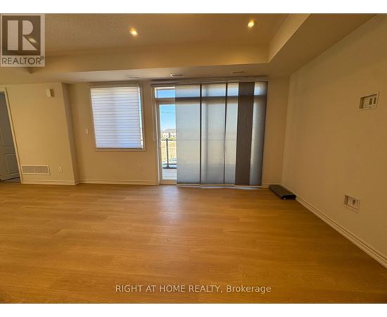 A spacious room with wooden flooring and a sliding glass door.