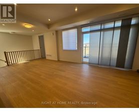 A spacious room with wooden flooring and large windows.