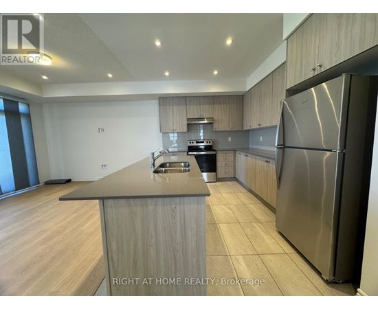 A modern kitchen with a stainless steel refrigerator and wooden cabinets.
