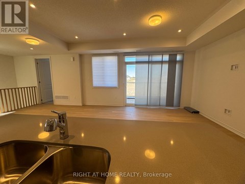 A spacious room with a sink and a window with blinds.