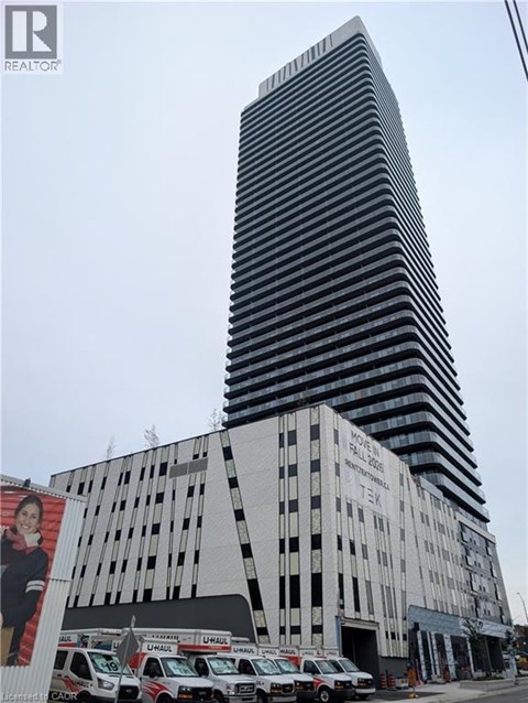 A tall building with a black and white striped facade stands next to a white building with a billboard on it.