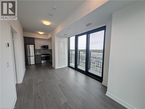 A spacious room with a kitchen area and sliding glass doors leading to a balcony.