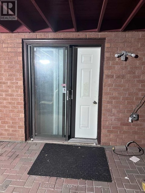 A door with a glass panel is closed and there is a doormat in front of it.
