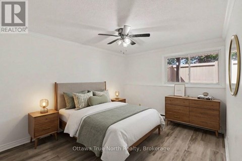 A bedroom with a bed, nightstands, and a ceiling fan.