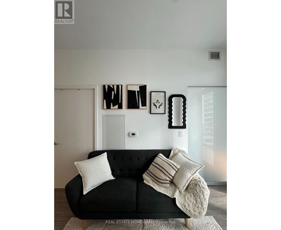 A black couch with white pillows in a room.