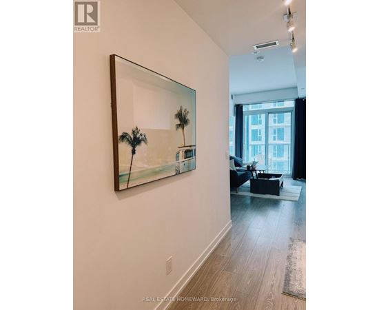 A painting of a palm tree is hanging on a white wall.