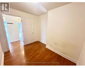A room with wooden floors and white walls, with a door on the left side.