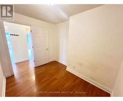 A room with wooden floors and white walls, with a door on the left side.