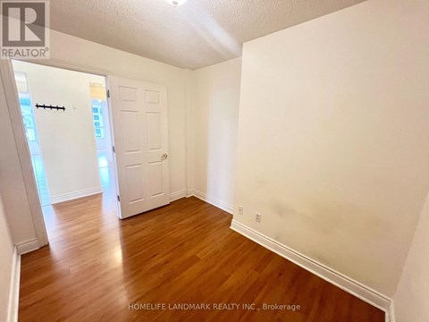A room with wooden floors and white walls, with a door on the left side.