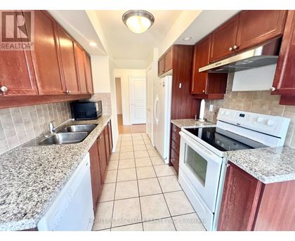 A kitchen with brown cabinets and white appliances.