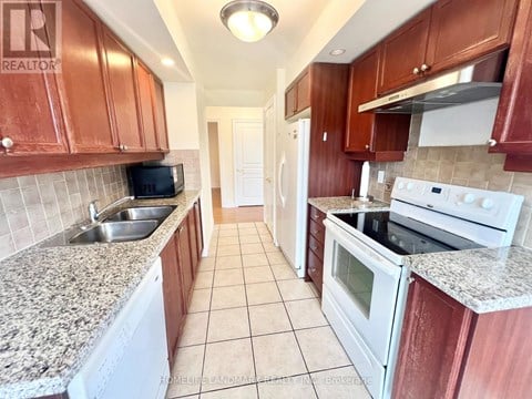 A kitchen with brown cabinets and white appliances.