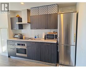 A modern kitchen with dark wood cabinets and stainless steel appliances.