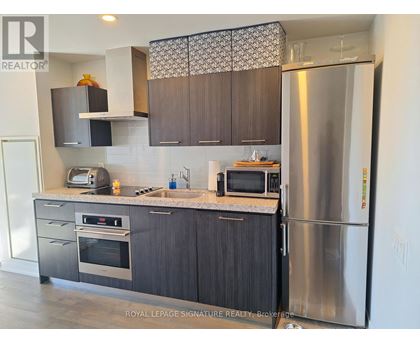 A modern kitchen with dark wood cabinets and stainless steel appliances.