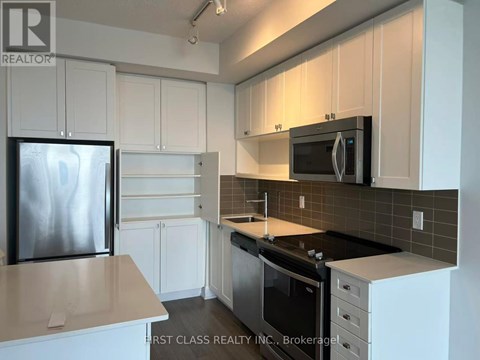 A kitchen with white cabinets and a black fridge.