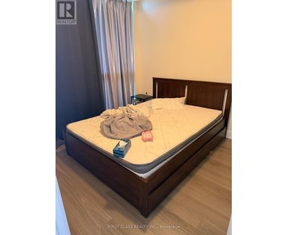 A bed with a wooden headboard and footboard with a white mattress and a grey blanket on it.