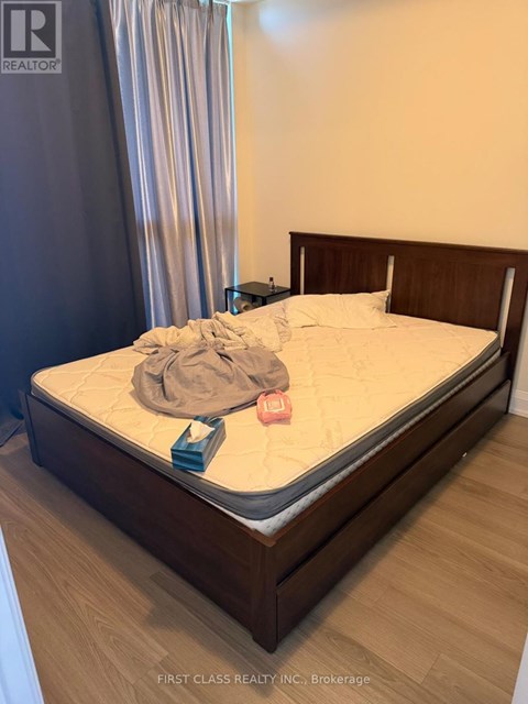 A bed with a wooden headboard and footboard with a white mattress and a grey blanket on it.