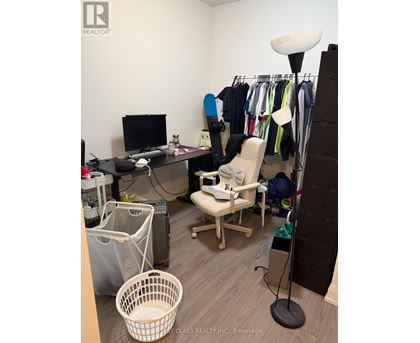 A room with a desk, chair, and clothes hanging on a rack.