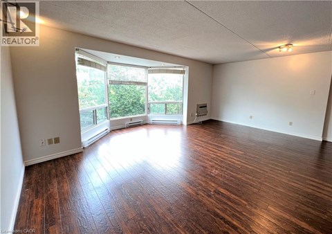 A spacious room with wooden flooring and a large window.