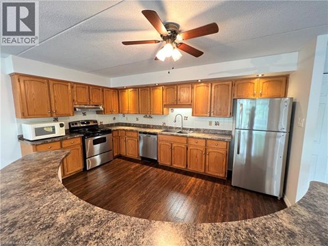 A kitchen with wooden cabinets and a stainless steel refrigerator.