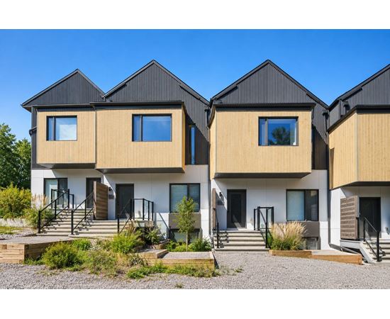 A modern house with a black roof and wooden sidings.