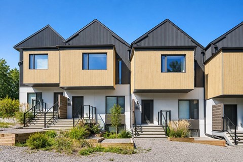 A modern house with a black roof and wooden sidings.