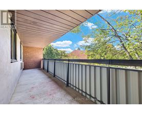 A balcony with a metal railing and a view of trees and a house.
