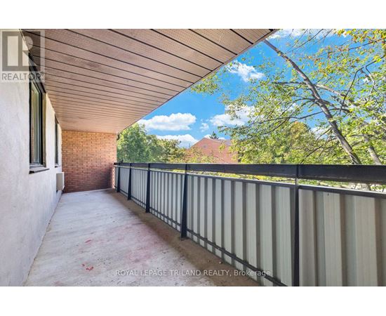 A balcony with a metal railing and a view of trees and a house.